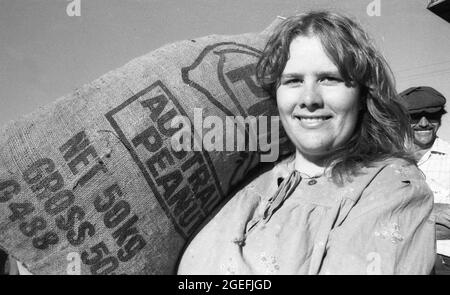 KINGAROY, QUEENSLAND, AUSTRALIA, 28 APRILE 1984: Una giovane donna non identificata totes un sacchetto di 50kg delle arachidi all'annuale festival di Peanut di Kingaroy, 1984. Scansionato da negativi originali per la pubblicazione di giornali. Foto Stock