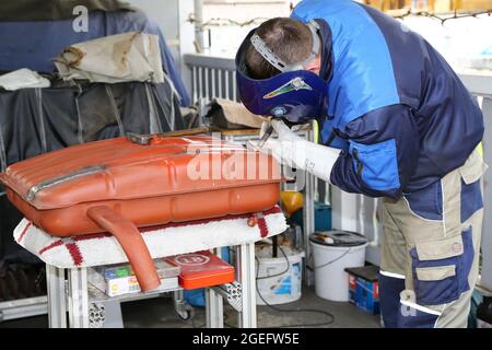 Primo piano di un uomo che ripara la parte della vettura per il rifornimento di benzina in officina Foto Stock