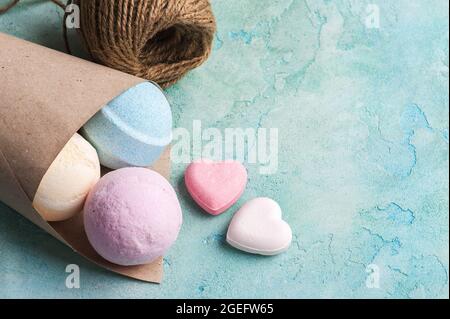 Bombe da bagno blu, vaniglia e fragola nel cono su fondo di cemento turchese Foto Stock