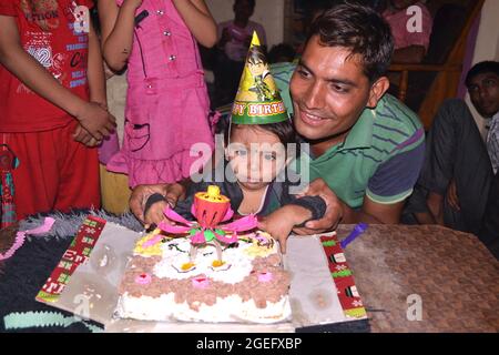 25-06-2020 Indore M.P. India. Il ragazzo del piccolo villaggio sta godendo una torta al suo compleanno, suo padre e altri bambini alla festa di compleanno. Foto Stock