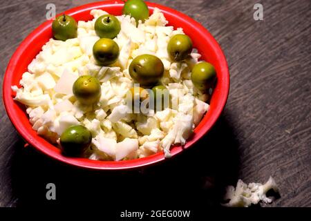 Bacche e cavolfiore tritato tenuti in un cestino rosso per verdure e insalate Foto Stock