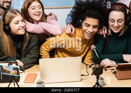 Felici amici diversi divertirsi in streaming online utilizzando il computer portatile e l'app per smartphone - Focus principale su african man face Foto Stock