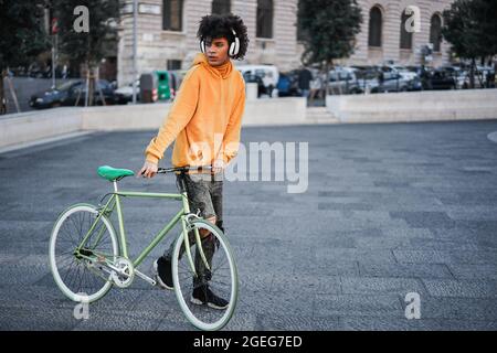 Giovane pilota africano che si diverte ad ascoltare musica in giro per la città - concentrarsi sulle mani che tengono la bicicletta Foto Stock