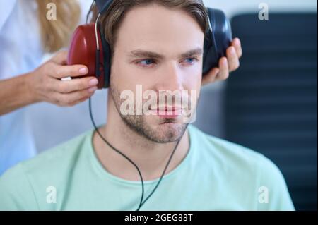 Indossare le cuffie al paziente durante una procedura di screening uditivo Foto Stock