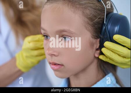 Primo piano di ragazza e medici mani mettere su cuffie Foto Stock