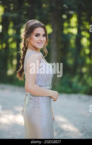 Una donna piuttosto giovane che indossa un abito elegante sta posando nel parco Foto Stock