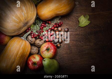 sfondo autunnale con zucca, frutta e noci su sfondo di legno scuro Foto Stock