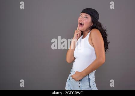 ragazza cinese di 20/24 anni con bandana su sfondo neutro, mettendo espressione divertente. Foto Stock