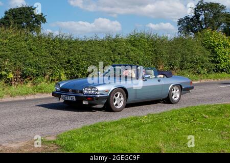 Una vista frontale di un'automobile auto cabriolet d'epoca con pilota in stile retrò Blue Jaguar XJ-S Convertible Foto Stock