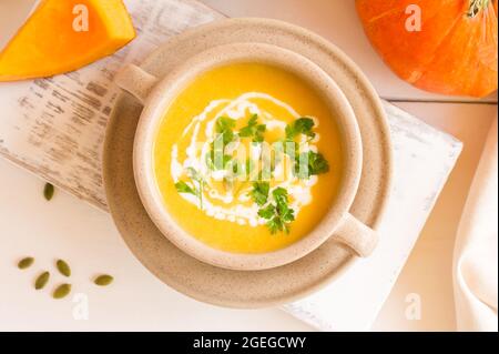 zuppa vegetariana di crema di zucca autunnale con semi di zucca servita in una ciotola con panna acida e prezzemolo. vista dall'alto Foto Stock
