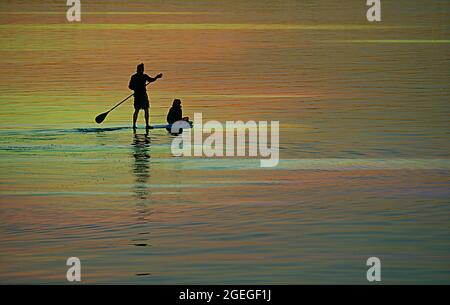 Tramonto con vista panoramica di una giovane coppia di silhouette su una pagaia a San Diego Bay in California, USA. Foto Stock