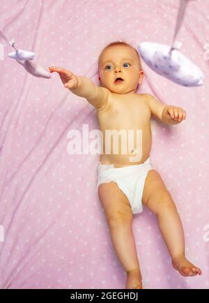 La bambina raggiunge con i giocattoli mobili a mano dall'alto Foto Stock