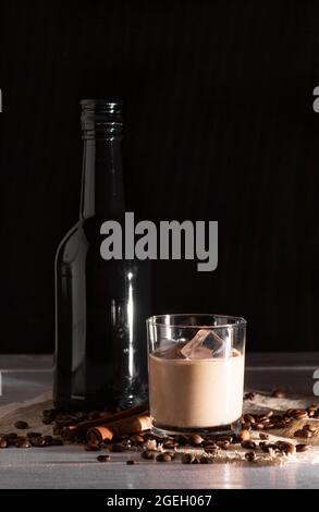 Un bicchiere di liquore al caffè con gelato e gelato. Chicchi di caffè, bottiglia nera. Foto Stock