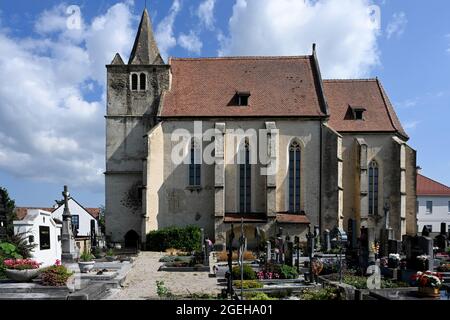 Vista laterale della chiesa cattolica nel villaggio d'Europa con un cimitero accanto ad essa. Foto Stock