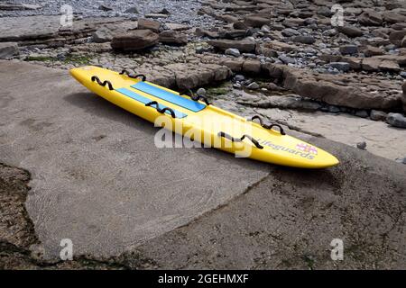 La grande tavola da surf dipinta in modo luminoso è stata progettata per un alto galleggiamento e due persone si siedono pronte sulla rampa di una spiaggia. Foto Stock