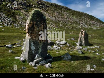 Visualizza NE di due pietre in piedi fiancheggiano un cairn in rovina sotto la collina rocciosa del Beorgs of Housetter, North Mainland, Shetland, Scozia, Regno Unito. Foto Stock