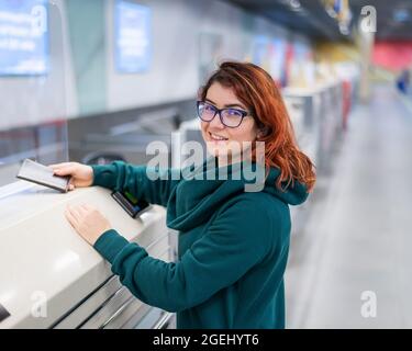 Una donna al banco check-in dell'aeroporto e dà il passaporto per acquistare un biglietto aereo Foto Stock