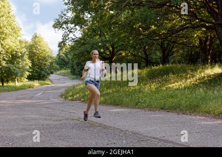 Giovane ragazza runner che corre lungo la pista tra il parco Foto Stock