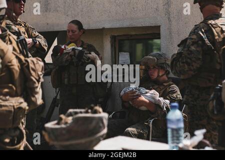 Marino Sgt. Nicole Gee con la 24a unità Marine Expeditionary Unit (MEU) (che è stata poi uccisa in azione durante l'esplosione della bomba ISIS-K a Kabul) secondo da sinistra, assegnato alla 24a unità Marine Expeditionary Unit (MEU) calma i bambini durante un'evacuazione all'Aeroporto Internazionale Hamid Karzai, Kabul, Afghanistan, 20 agosto. I membri del servizio degli Stati Uniti e i partner della coalizione stanno assistendo il Dipartimento di Stato con un'operazione DI evacuazione non combattente (NEO) in Afghanistan. (STATI UNITI Foto del corpo marino di Sgt. Isaiah Campbell) Gee era uno dei 13 membri di servizio uccisi nel bombardamento. Foto Stock