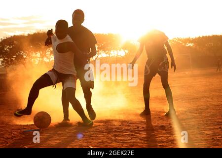 I giovani sono visti giocare a calcio al tramonto al campo profughi di Dzaleka. Dowa, Malawi. Foto Stock