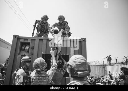 Le forze della coalizione britannica, le forze della coalizione turca e i marines statunitensi assistono un bambino durante un'evacuazione all'aeroporto internazionale Hamid Karzai, Kabul, Afghanistan, 20 agosto. I membri del servizio degli Stati Uniti stanno assistendo il Dipartimento di Stato con un'operazione di evacuazione non combattente (NEO) in Afghanistan. (STATI UNITI Foto del corpo marino di staff Sgt. Victor Mancilla) Foto Stock