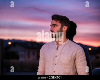 Attraente giovane uomo in piedi sullo sfondo del tramonto del sole Foto Stock
