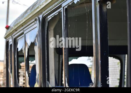 Bus dilapidato e arrugginito con finestre rotte in un'area remota. Foto Stock