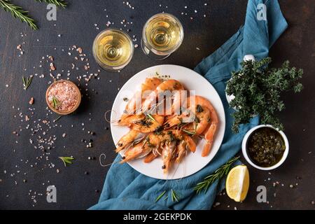 Gamberi su un piatto. Vino in bicchieri. Frutti di mare. Vista dall'alto. Cena Sfondo scuro Foto Stock