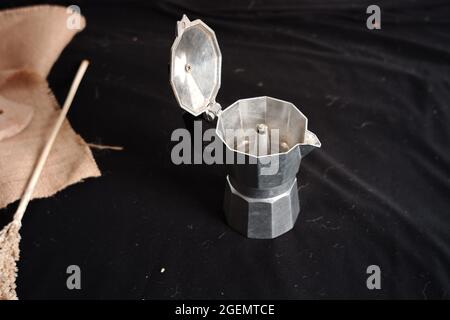 Tazza da caffè vuota in alluminio o bollitore isolato su sfondo nero in tessuto. Stampa fotografica minimale per materiale di design o per scrittura e testo Foto Stock