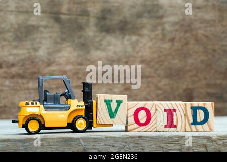 Carrello giocattolo giallo tenere il blocco di lettera V per completare la parola vuoto su sfondo di legno Foto Stock