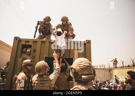 Le forze di coalizione del Regno Unito, le forze di coalizione turche e i marines degli Stati Uniti assistono un bambino durante un'evacuazione all'aeroporto internazionale Hamid Karzai, Kabul, Afghanistan, 20 agosto 2021. I membri del servizio USA stanno assistendo il Dipartimento di Stato degli Stati Uniti con un'operazione DI evacuazione non combattente (NEO) in Afghanistan. Credito obbligatorio: Victor Mancilla/US Marine Corps via CNP Foto Stock