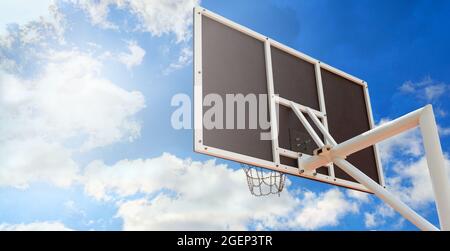 Backboard da basket con un cestino fatto di catene di ferro, da vicino contro il cielo blu. Spazio di copia. Vista ad angolo basso Foto Stock