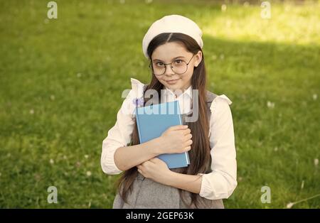 Elegante studentessa bambina studia con libro nel parco, imparando concetto Foto Stock