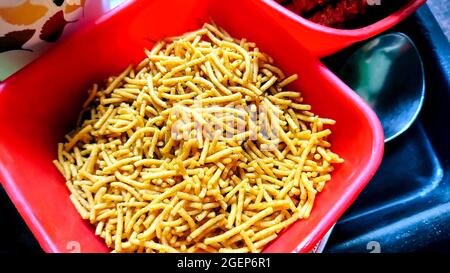 Famoso e amato snack indiano Alo Bhujia fatto di patate, servito in una ciotola rossa. E' il migliore spuntino indiano se servito con bevande. Foto Stock