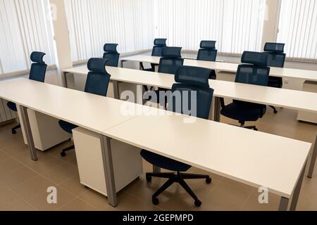 Sedie e scrivanie sono visibili in una piccola sala conferenze vuota. Foto Stock