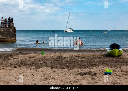 Persone in vacanza e andare per una nuotata in mare a Swanage Beach, Dorset, estate 2021 Foto Stock