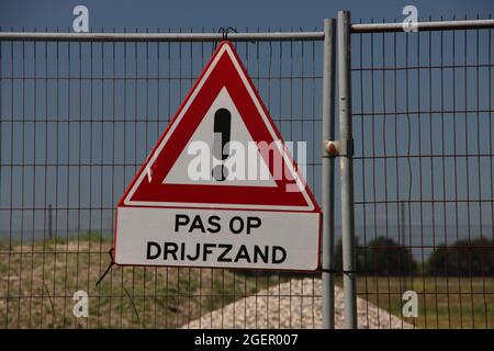 Cartello segnaletico per le sabbie mobili presso il cantiere di recinzione nei Paesi Bassi Foto Stock