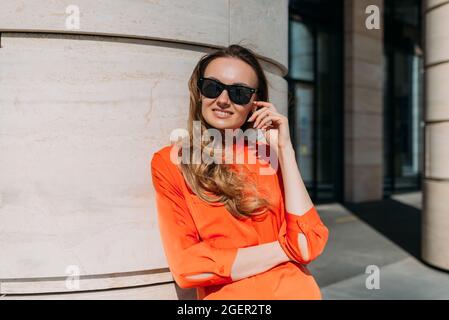 Donna modello di stile di trent'anni in posa sulla macchina fotografica indossando occhiali nel centro della città Foto Stock