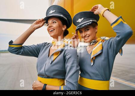 Gioiose hostess in uniforme da parte di un aereo atterrato Foto Stock