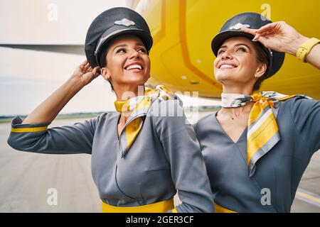 Stewardesses in caps pilota in piedi all'aeroporto Foto Stock