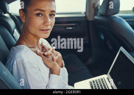 Sorprende il passeggero femminile con un computer portatile in automobile Foto Stock