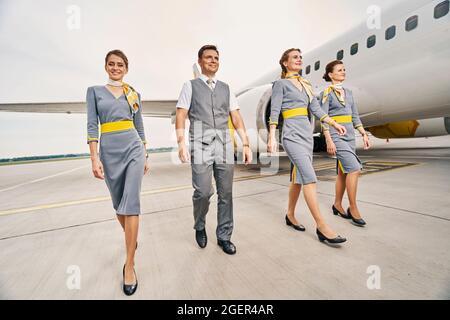 Sorridente equipaggio di cabina in uniformi che cammina avanti Foto Stock