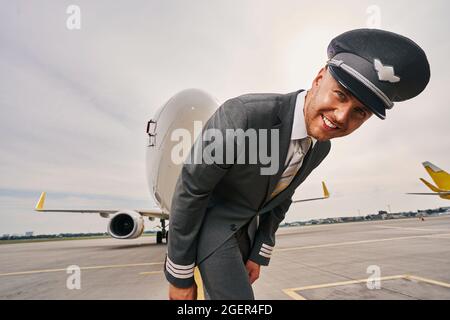 Allegro e attraente capitano della compagnia aerea in uniforme sulla pista Foto Stock