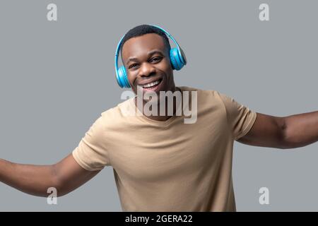 Giovane uomo con pelle scura in cuffie che ascoltano musica Foto Stock