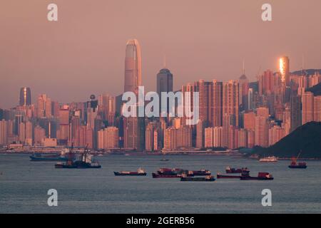 Il tramonto si riflette in un alto blocco di appartamenti a Mid-level, con i grattacieli di Central, Isola di Hong Kong, nella luce rosa del tramonto Foto Stock