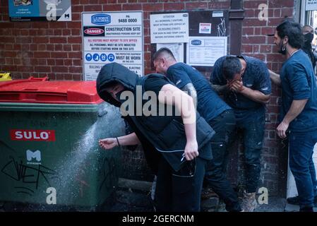 Melbourne, Australia. 21 agosto 2021. I manifestanti anti anti-bloccanti lavano il pepe spruzzare via le loro facce. Credit: Jay Kogler/Alamy Live News Foto Stock