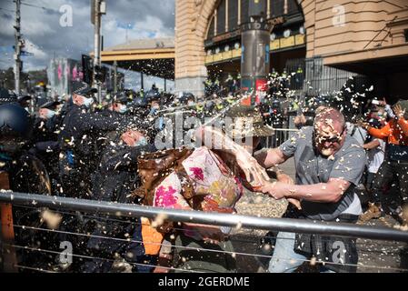 Melbourne, Australia. 21 agosto 2021. Un protester anti-lock-down che aiuta un altro come sono colpiti con pepper spray. Credit: Jay Kogler/Alamy Live News Foto Stock