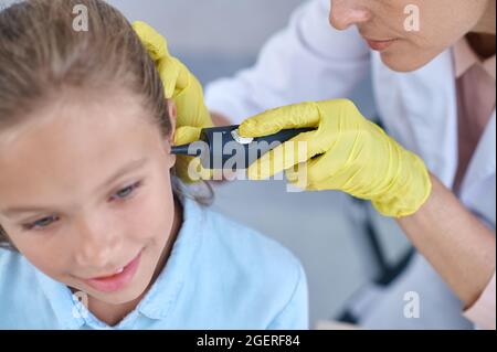 Medico esaminano le ragazze orecchio con dispositivo Foto Stock