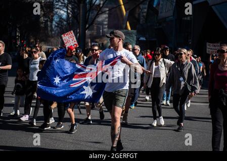 Melbourne, Australia. 21 agosto 2021. Un uomo con una bandiera australiana si sposa con i manifestanti anti di blocco mentre inghiottiscono le strade di Melbourne nelle loro migliaia. Credit: Jay Kogler/Alamy Live News Foto Stock