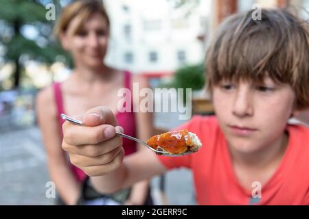 Ragazzo mangiando trilece a, trilece, trileche - dessert trilece tradizionale, Gjirokaster, Albania, Foto Stock